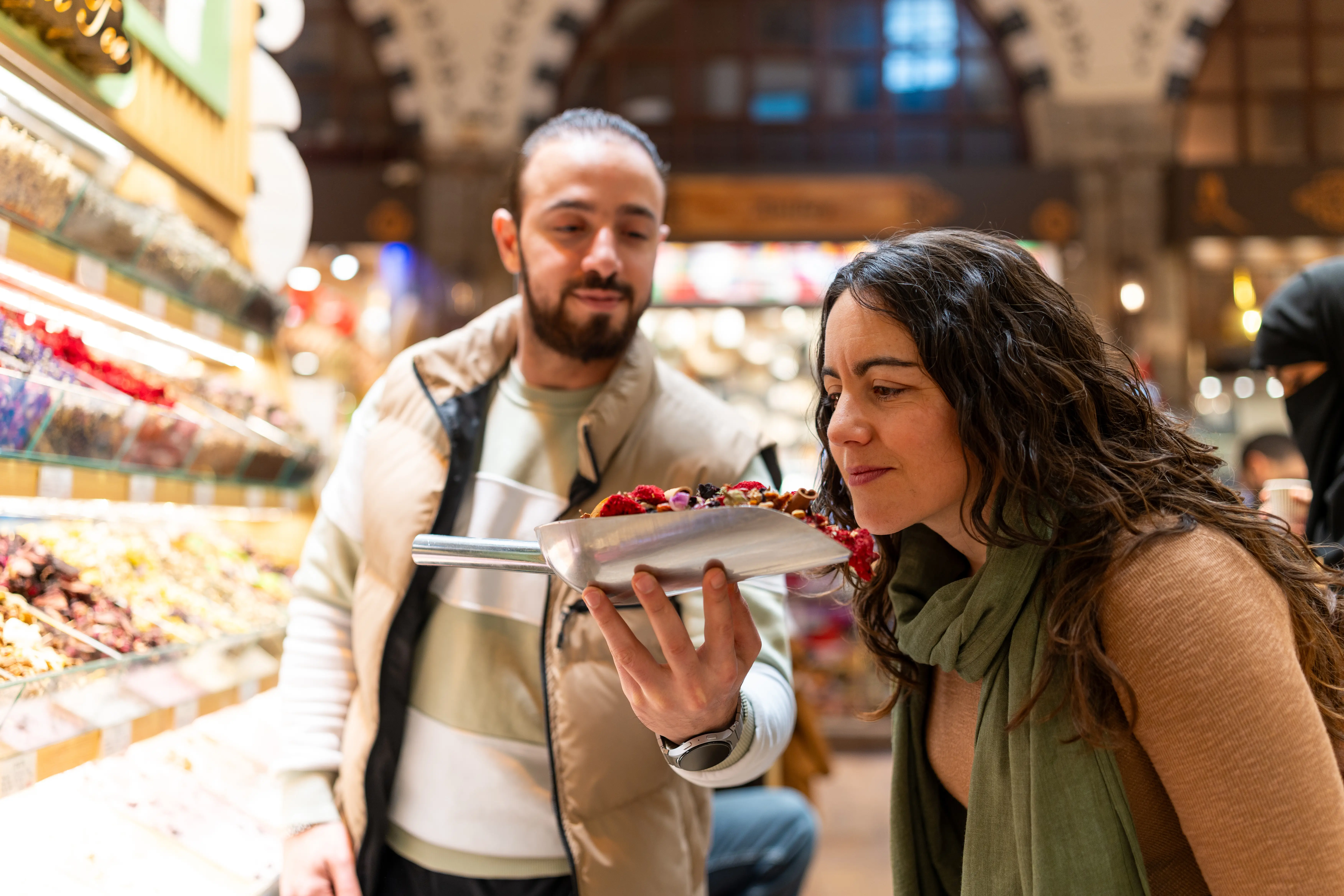 A vendor offering dried fruits for a customer to smell at an Istanbul market