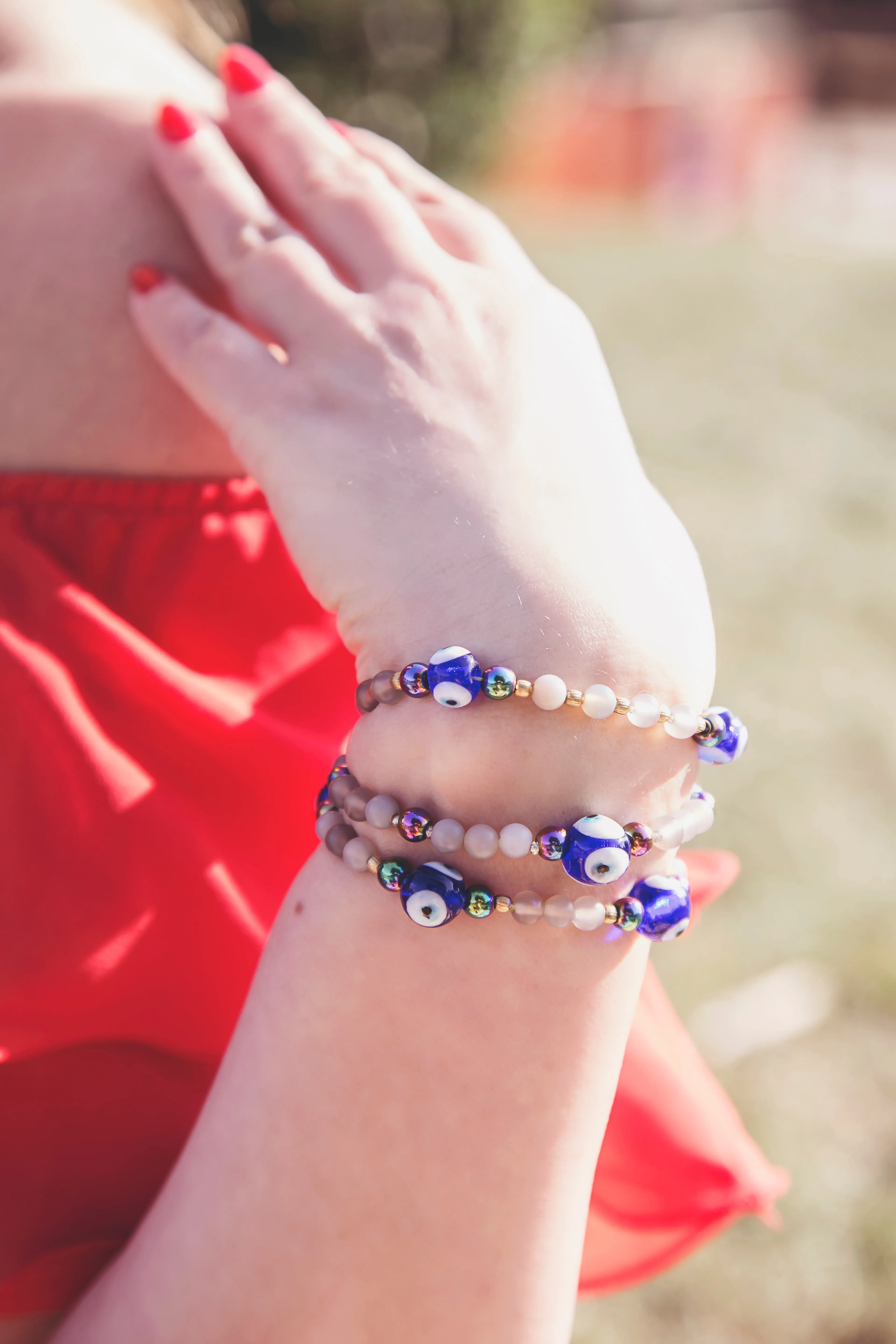 A woman&#x27;s hand showing bead bracelets featuring the blue-and-white nazar boncuğu evil-eye charm