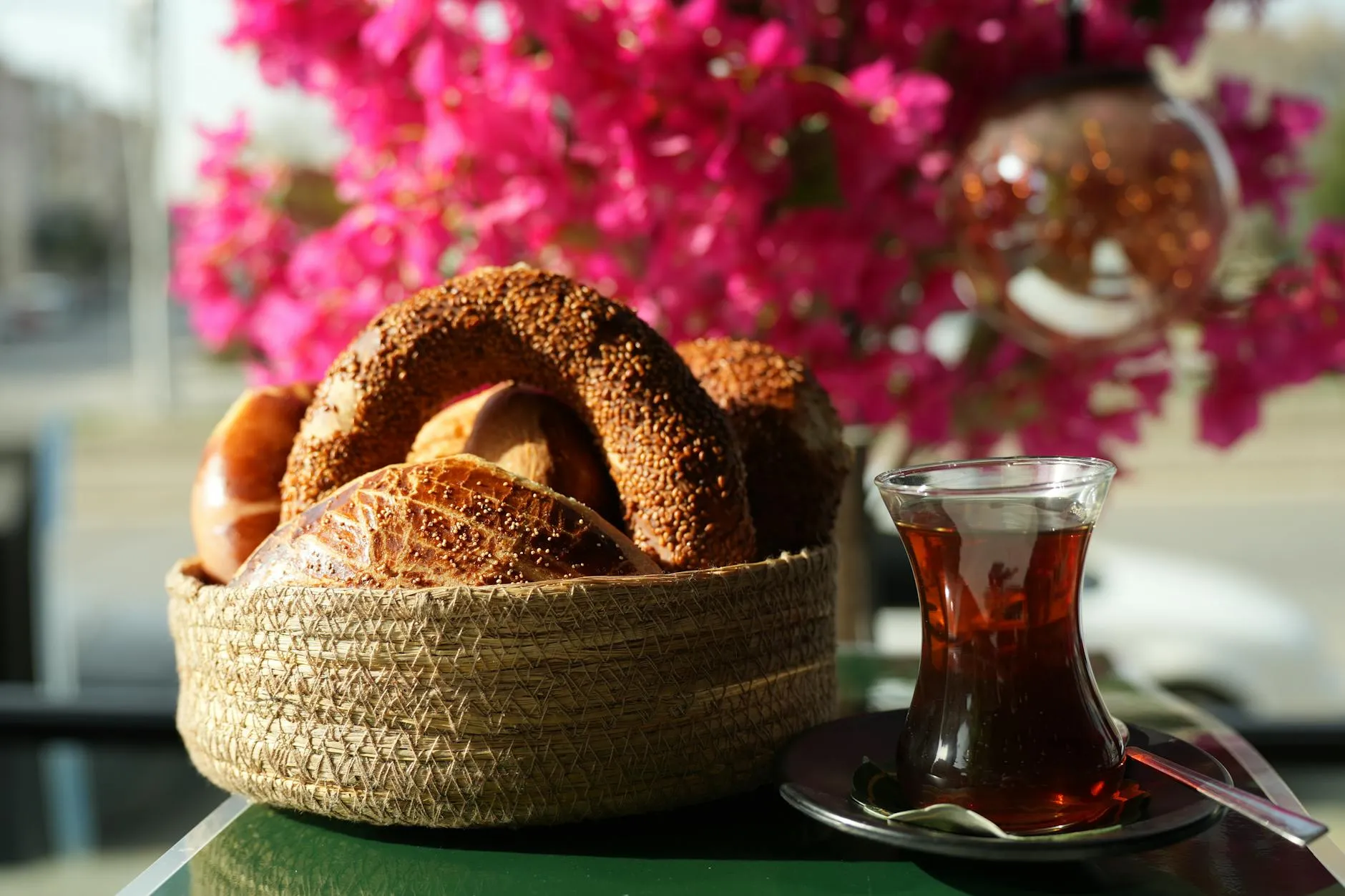 A sesame simit bread ring next to a tulip-shaped glass of Turkish tea