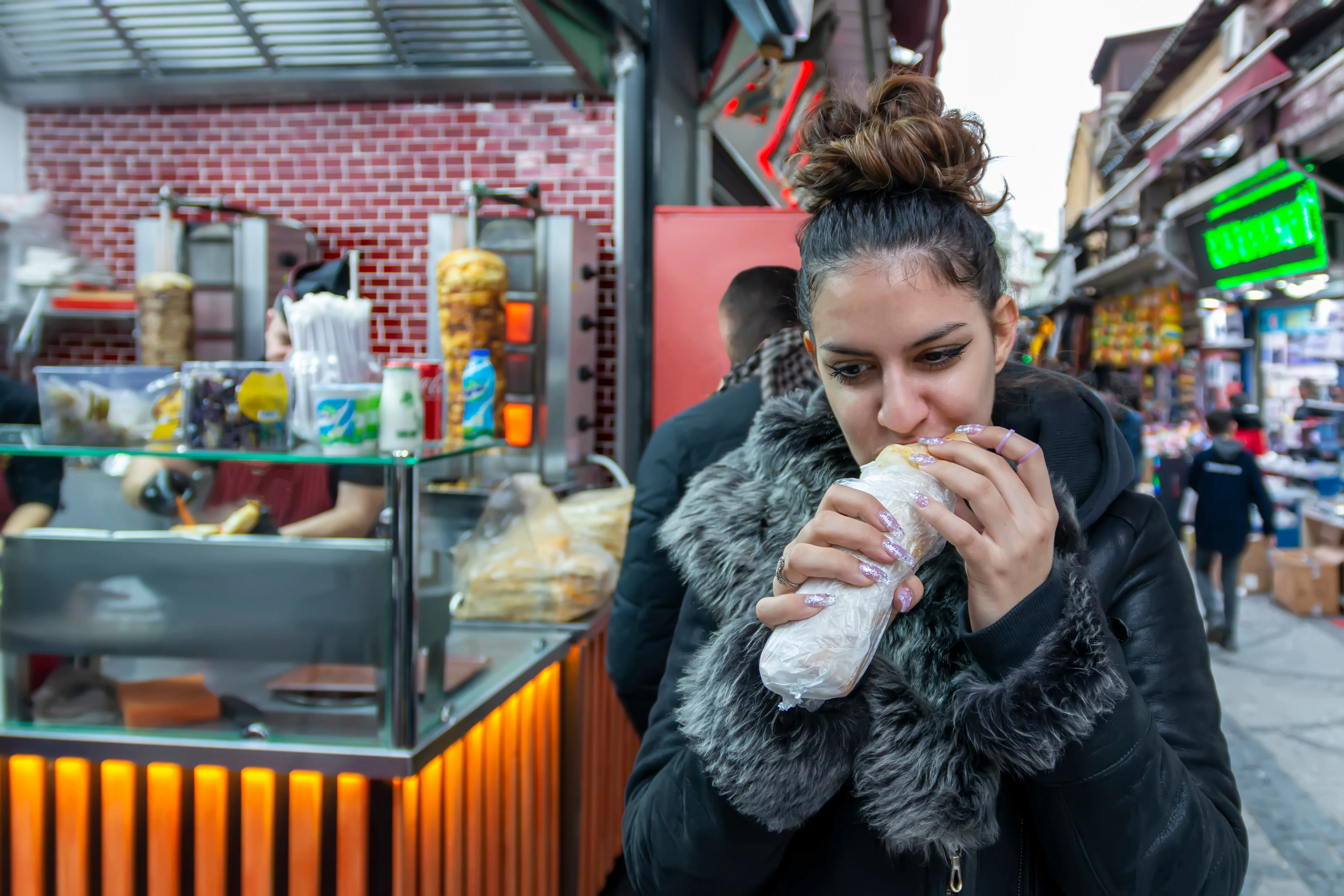A young traveler buying and tasting street food from a local Istanbul vendor