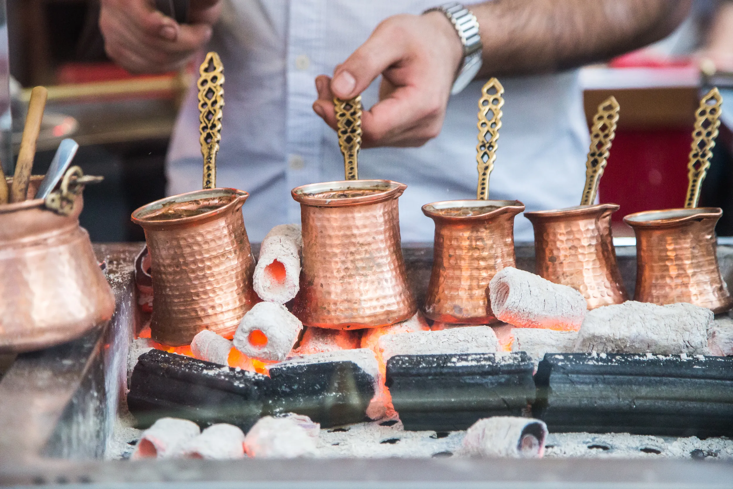 A Turkish copper coffee pot and tulip cup set on a wooden table in Kadıköy