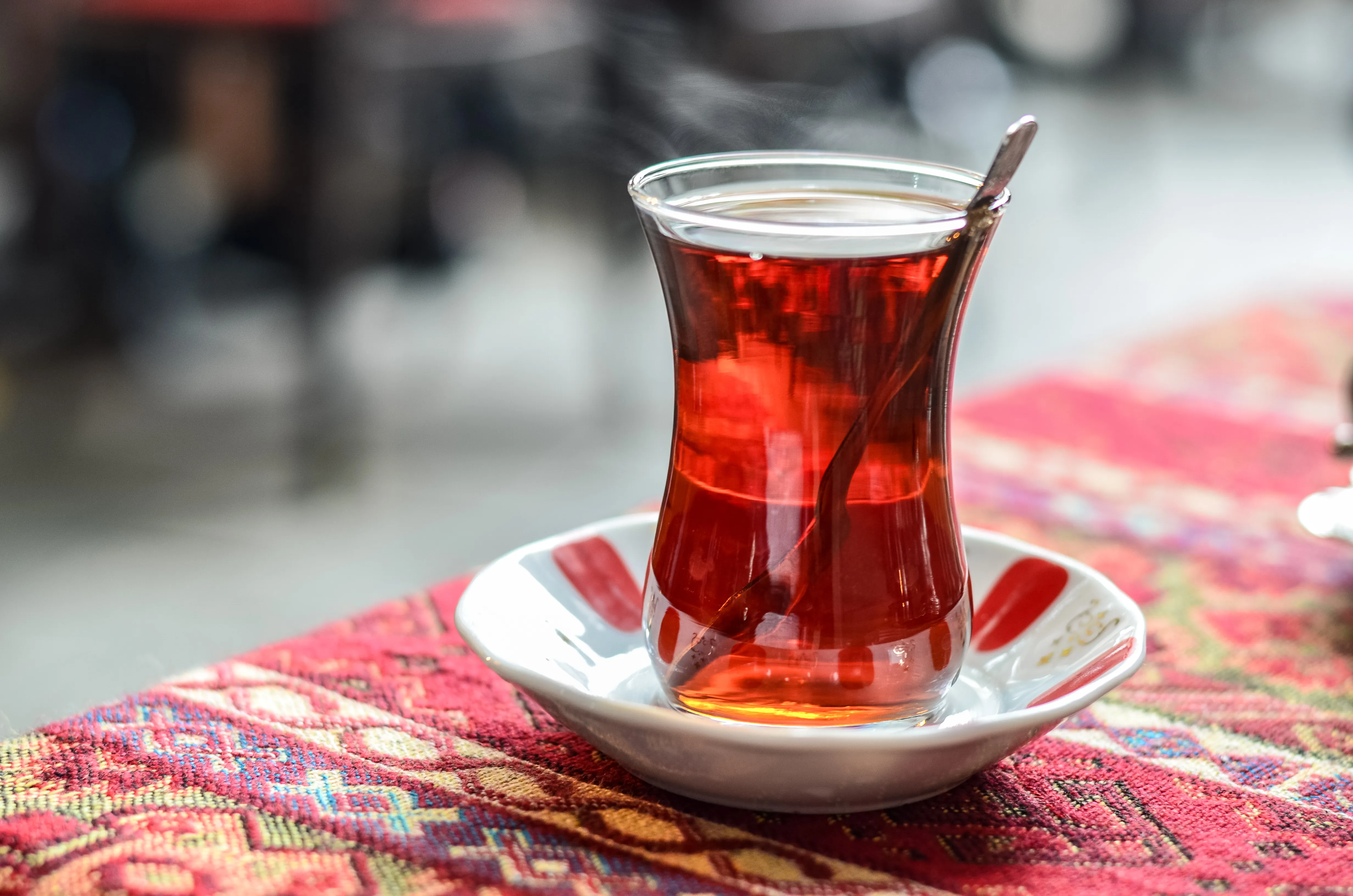 A tulip-shaped glass of Turkish black tea with a soft bokeh background