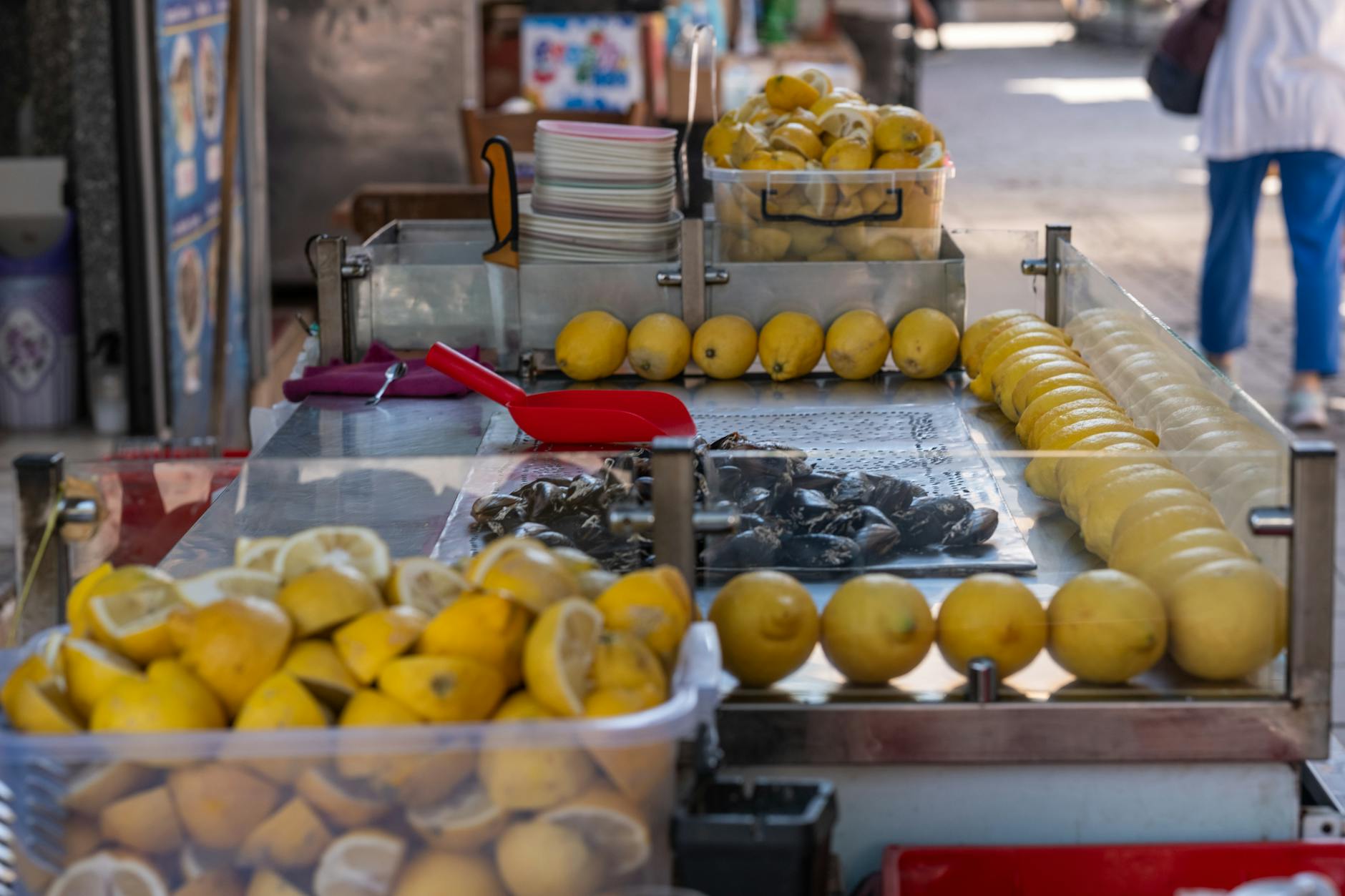 A Turkish midye dolma street cart with mussels stuffed with rice, piled lemons and a red scoop