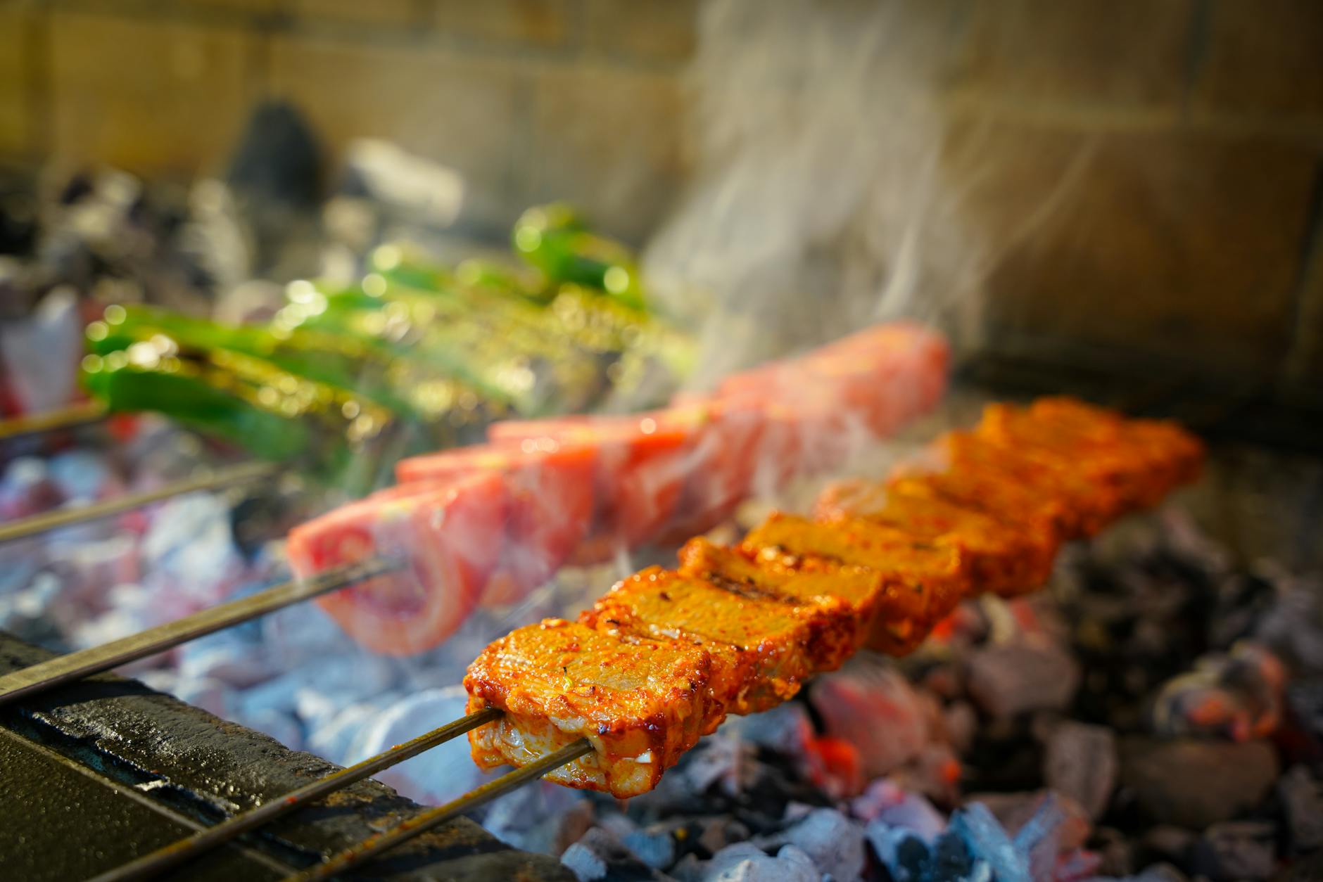 Skewers of spiced Turkish kebab meat and green peppers cooking over glowing charcoal at an ocakbaşı grill